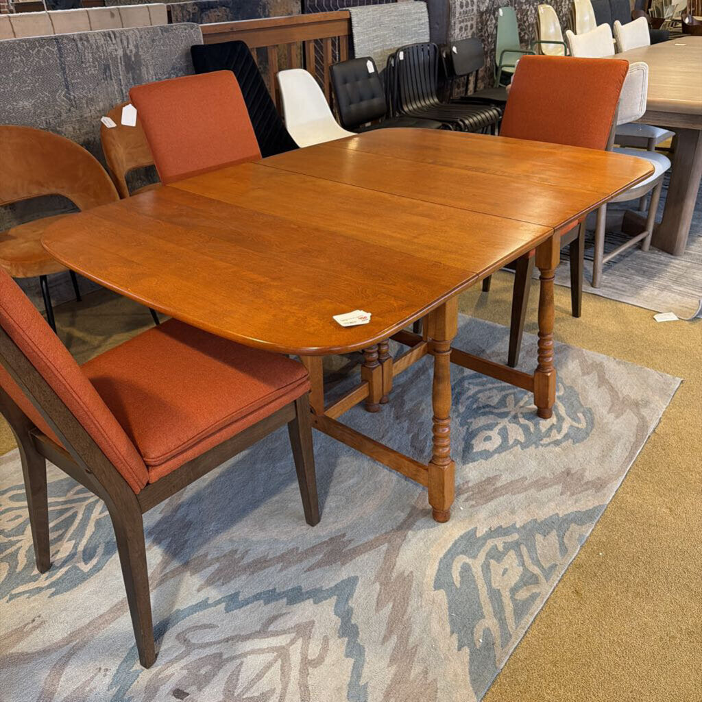 Wooden dining table with orange cushioned chairs on a patterned rug