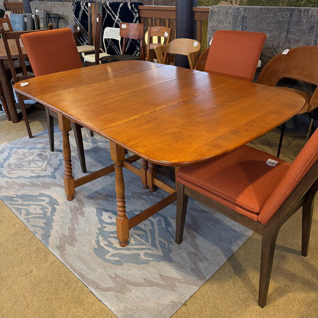 Wooden dining table with orange cushioned chairs on a patterned rug