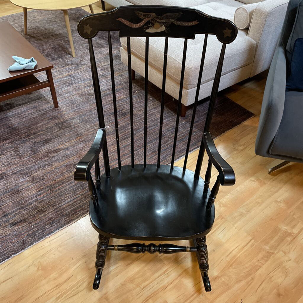 Black wooden chair in a living room setting with a couch and coffee table.