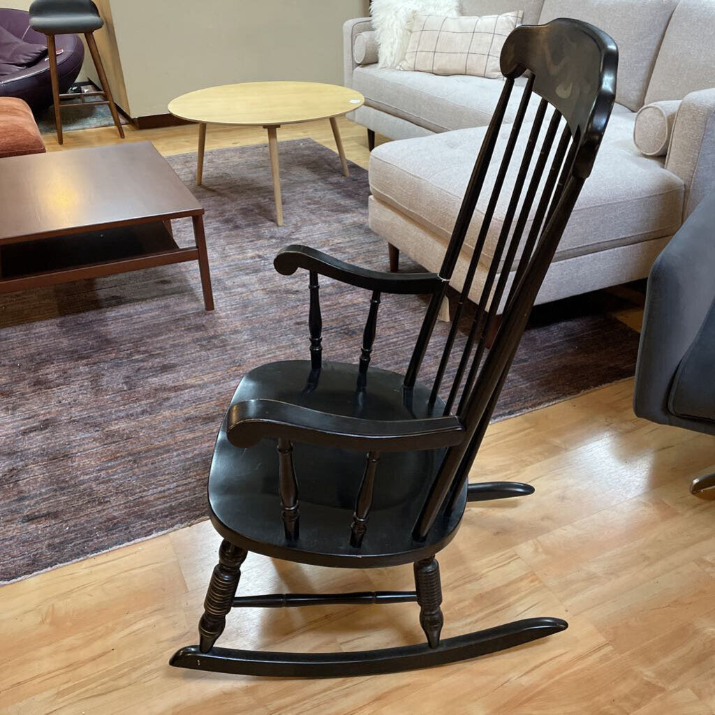 Black rocking chair in a living room setting with furniture and decor.