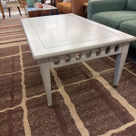 White coffee table with decorative cutouts on a patterned brown and beige rug