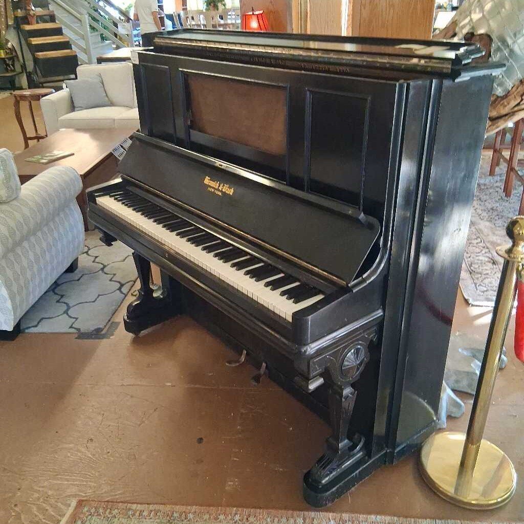 Black upright piano in a room with furniture and decor