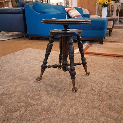 Vintage-style wooden bar stool in a living room setting with blue sofa and rug.