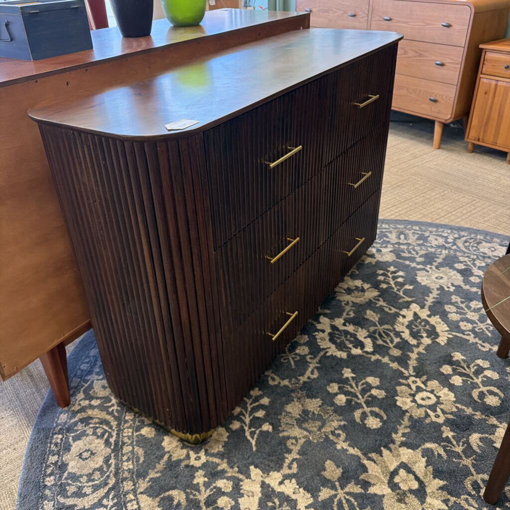 Dark wood dresser with gold handles on a patterned rug