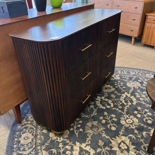 Dark wood dresser with gold handles on a patterned rug