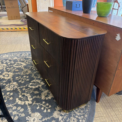 Wooden dresser with ribbed design on a patterned carpet