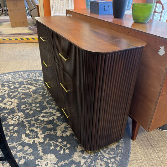 Wooden dresser with ribbed design on a patterned carpet