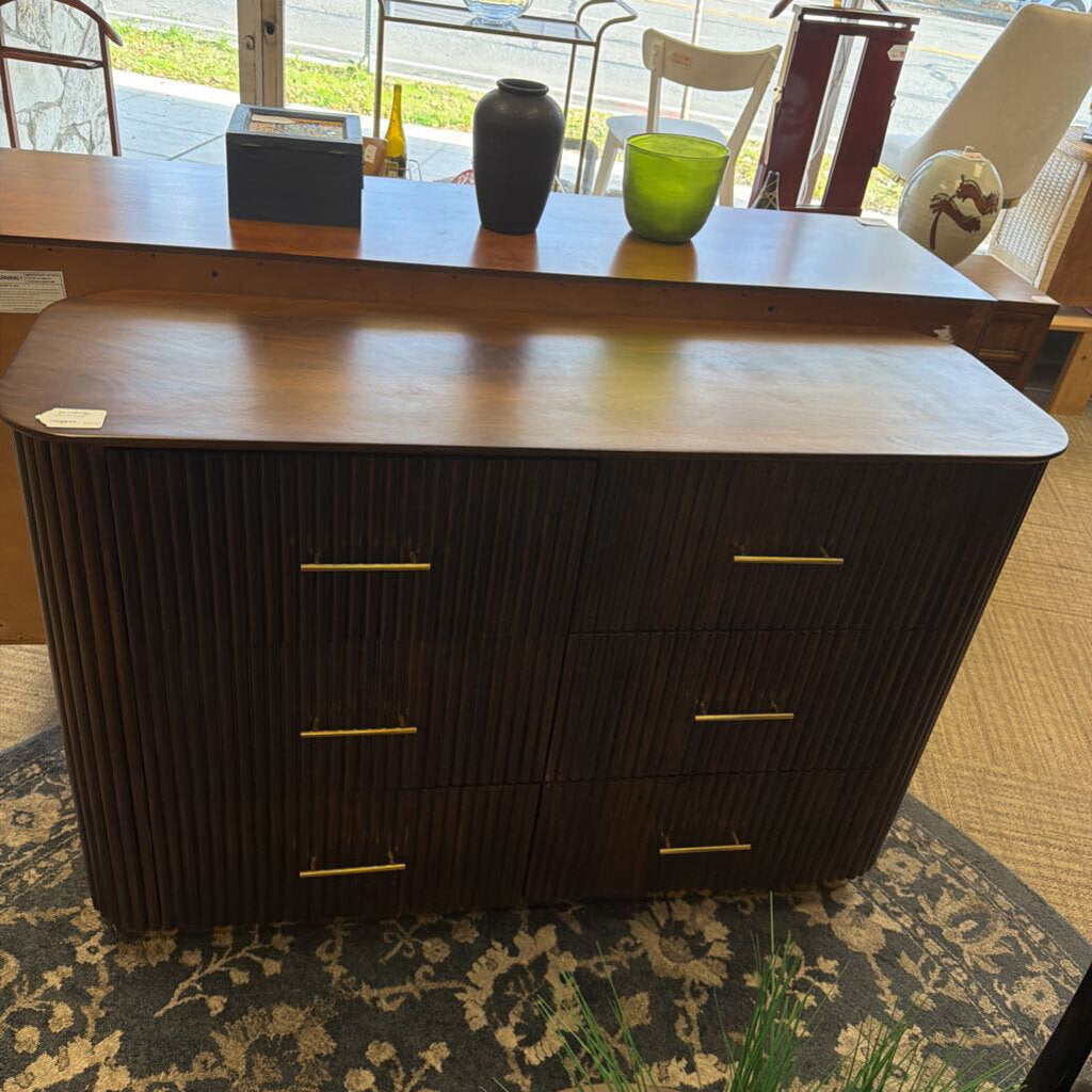 Dark wood dresser with gold handles on a patterned rug