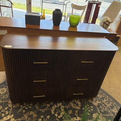 Dark wood dresser with gold handles on a patterned rug