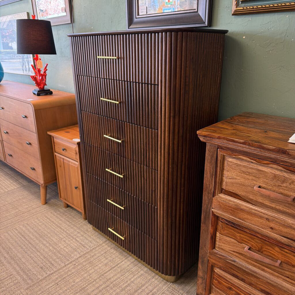 Wooden dresser with vertical slats in a room with other furniture and decor.