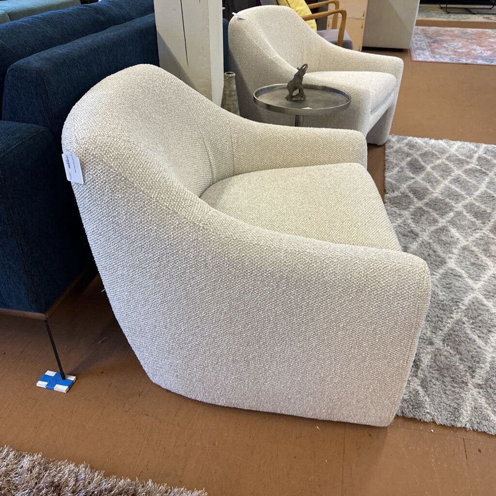Beige armchair in a showroom setting with other furniture and decor items.