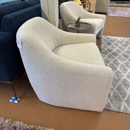 Beige armchair in a showroom setting with other furniture and decor items.