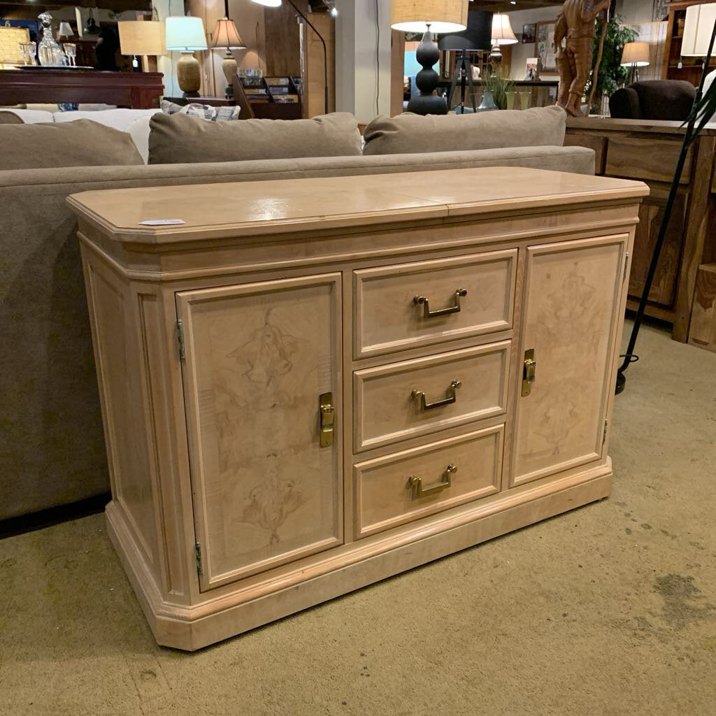 Beige sideboard with drawers and doors in a furniture store setting