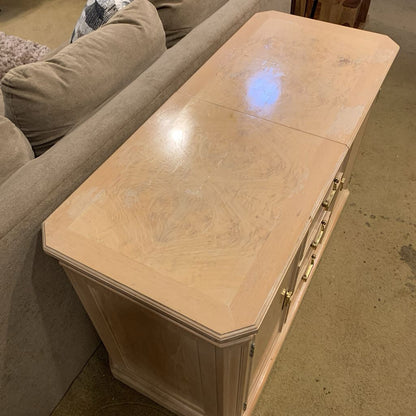 Wooden side table with marble-like finish next to a beige sofa.