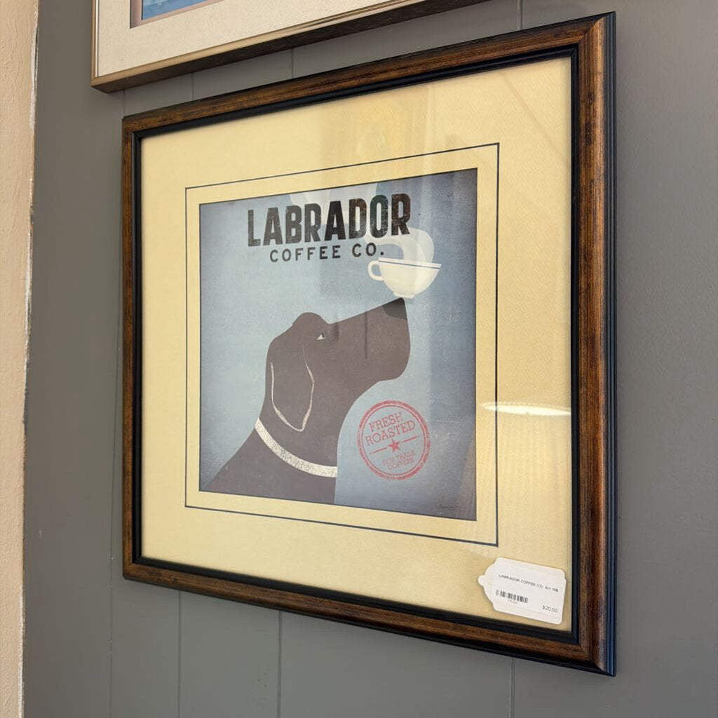 Framed poster of a dog drinking coffee with 'Labrador Coffee Co.' text on a gray wall.