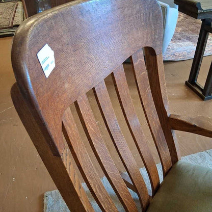 Wooden chair with a green cushion on a wooden floor.