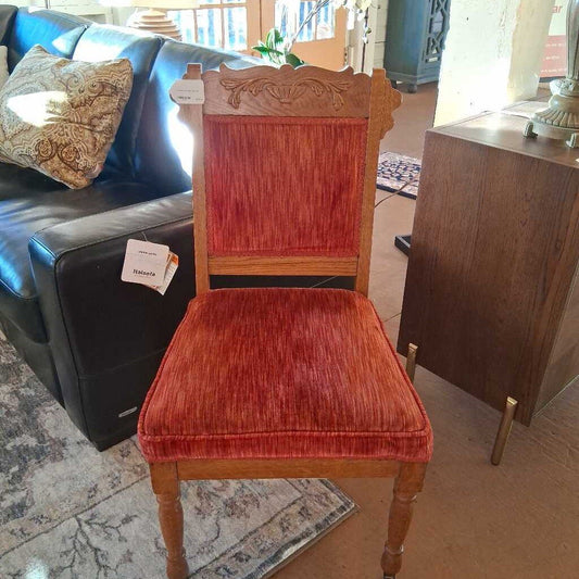 Wooden chair with red velvet seat and backrest in a living room setting.