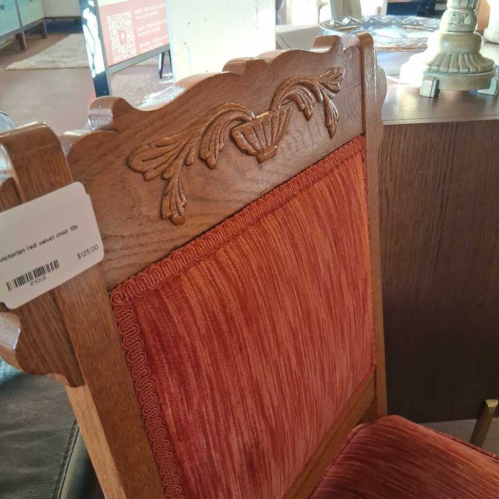 Wooden chair with red cushioned seat and backrest in a store setting