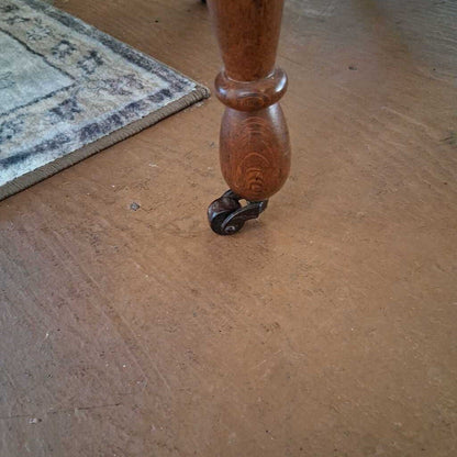 Wooden leg with a metal caster on a wooden floor