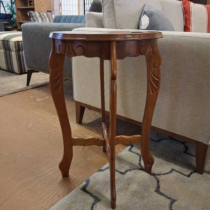 Wooden side table in a living room setting with a sofa and rug.