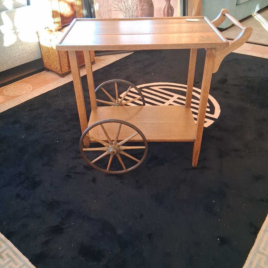 Wooden serving cart with wheels on a dark surface