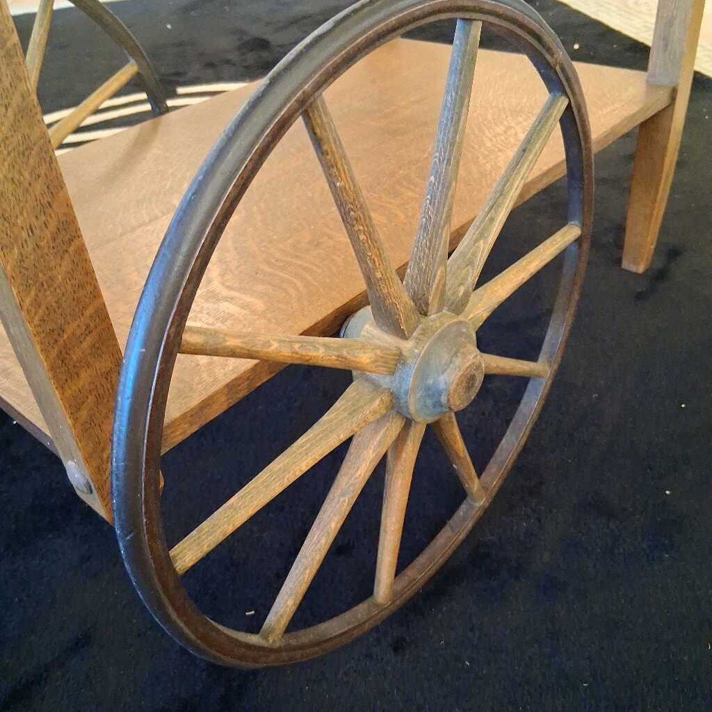 Wooden wheel with metal rim on a cart-like structure.
