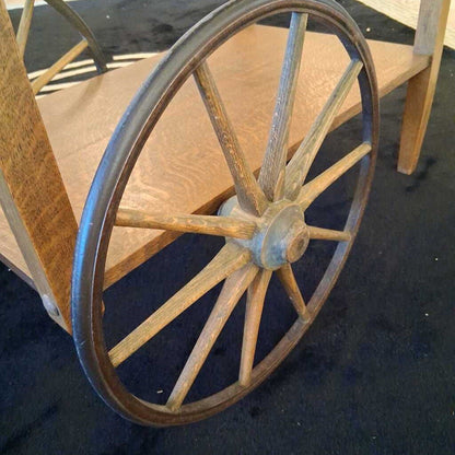 Wooden wheel with metal rim on a cart-like structure.
