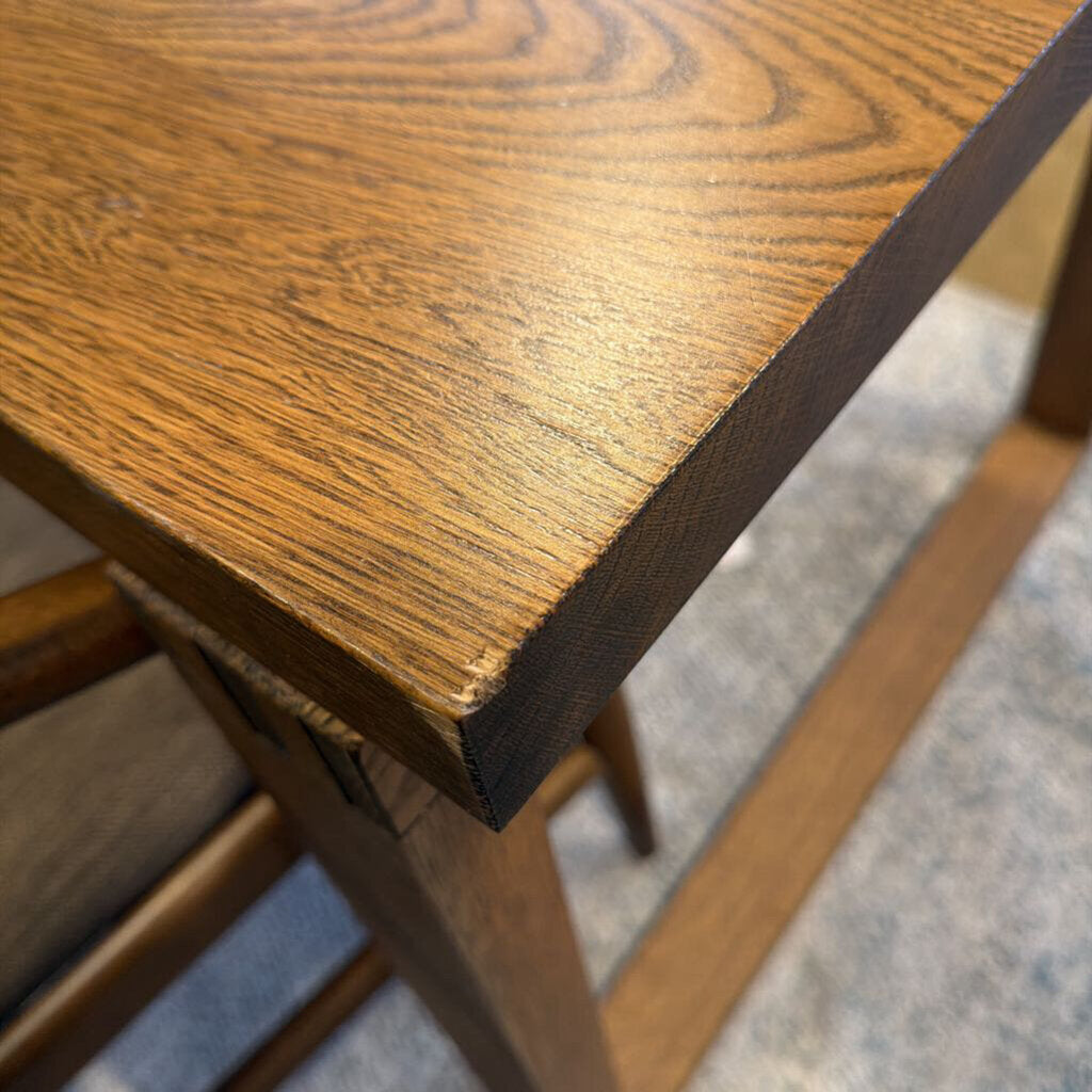 Close-up of a wooden stool with a focus on the seat and legs.