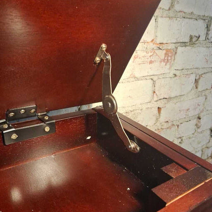 Wooden desk with a metal lever mechanism against a brick wall.