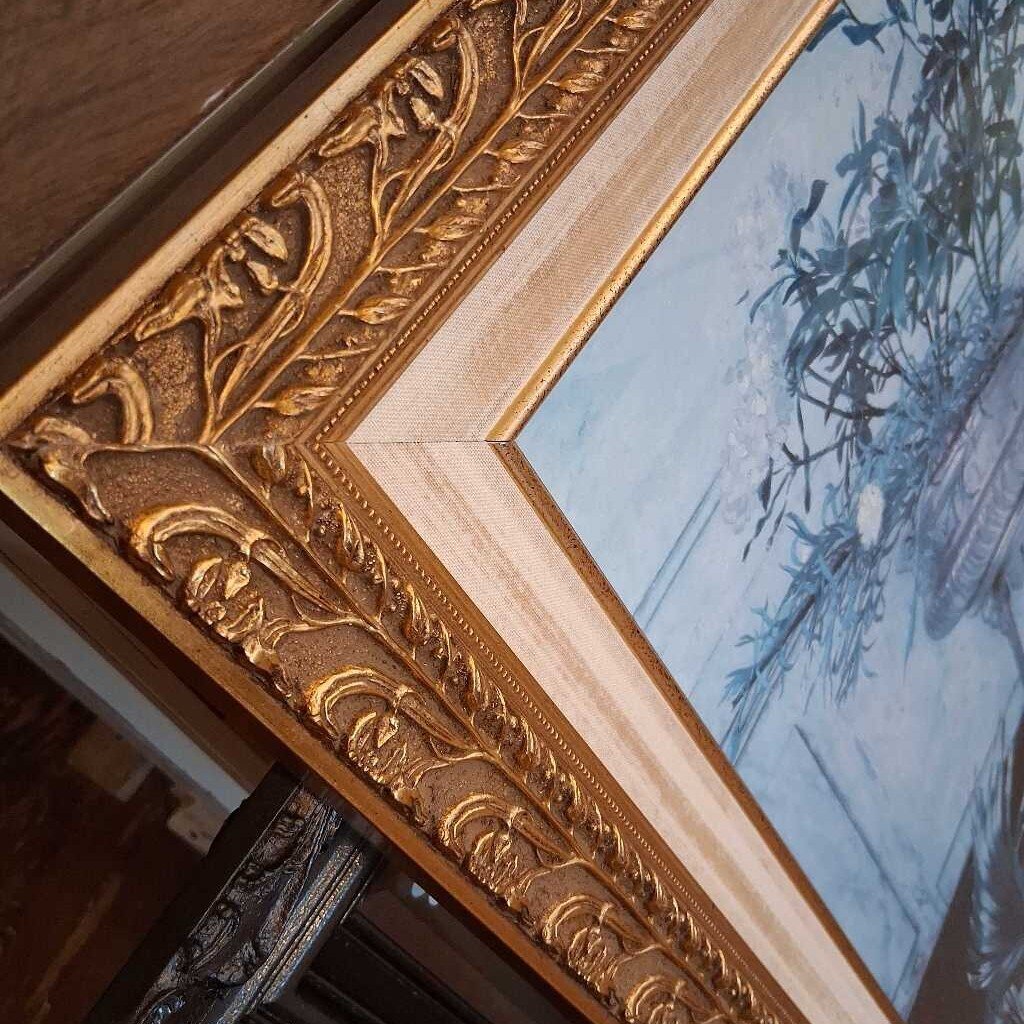 Close-up of an ornate gold frame with a painting inside
