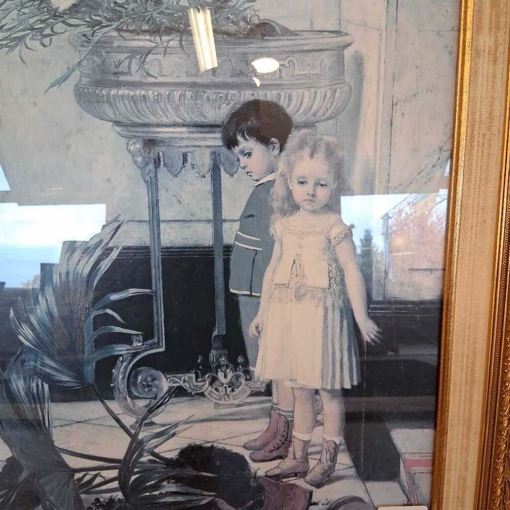 Framed artwork of two children by a fireplace with decorative elements.