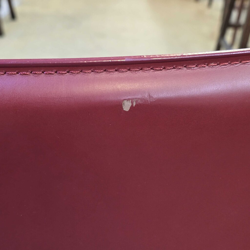 Close-up of a red leather surface with a visible scratch.
