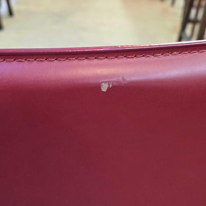 Close-up of a red leather surface with a visible scratch.