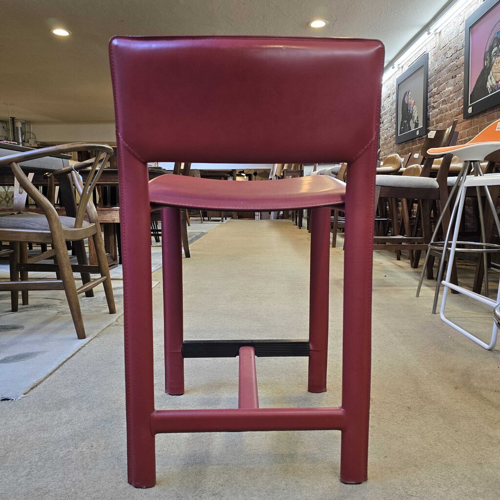 Red bar stool in a casual dining setting with tables and chairs.