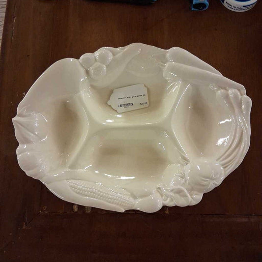 White ceramic dish with decorative elements on a wooden surface