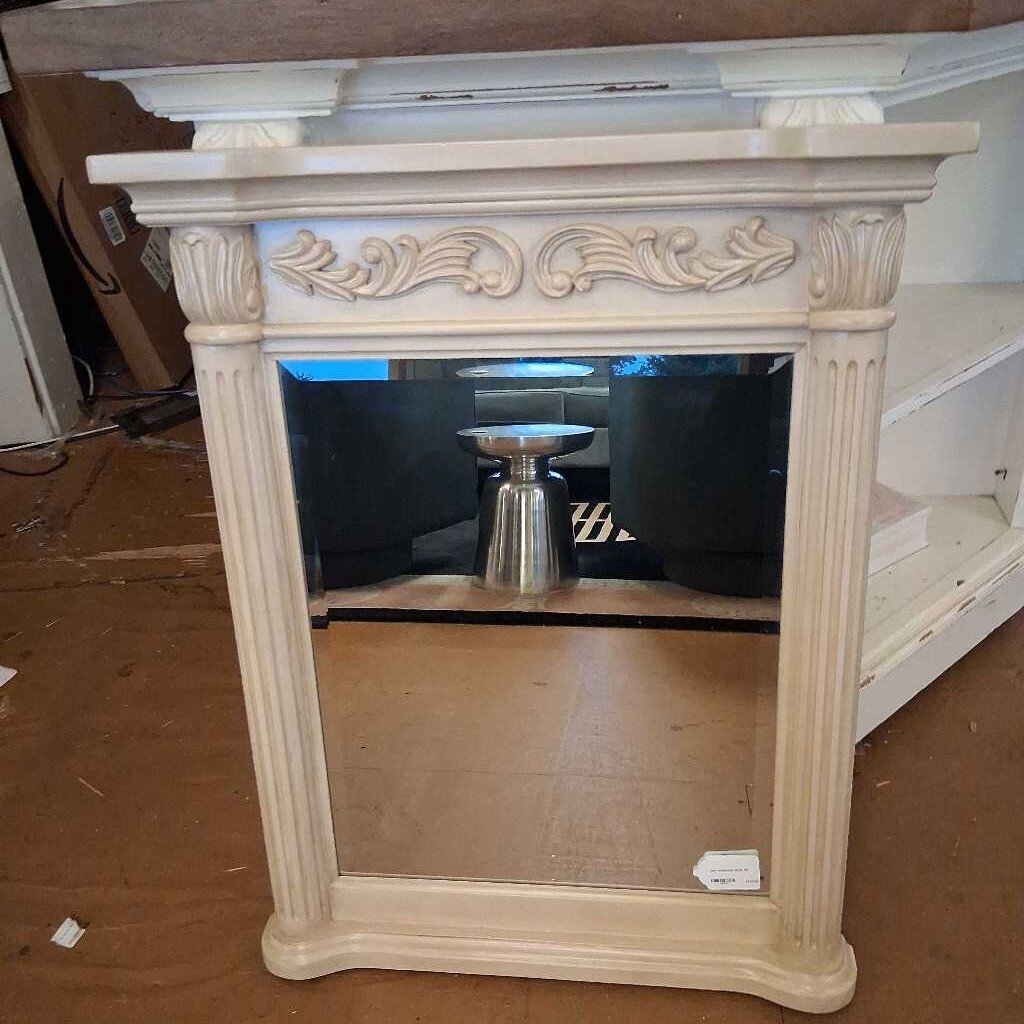 Decorative mirror with ornate frame on a brown floor