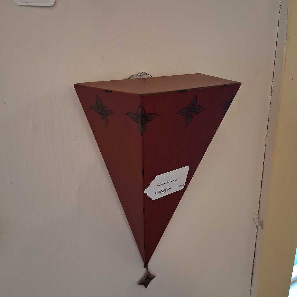 Triangular wooden shelf with decorative elements on a wall.