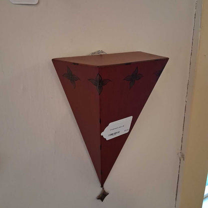 Triangular wooden shelf with decorative elements on a wall.