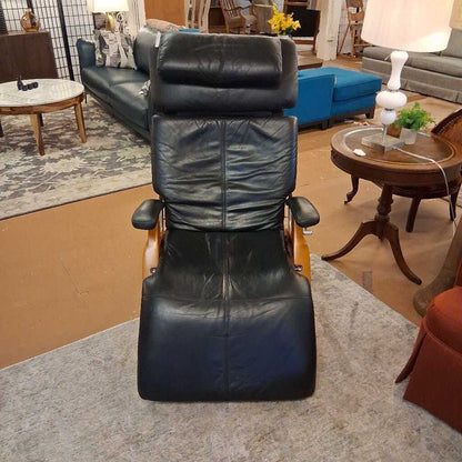 Black leather recliner chair in a showroom setting with furniture and decor.