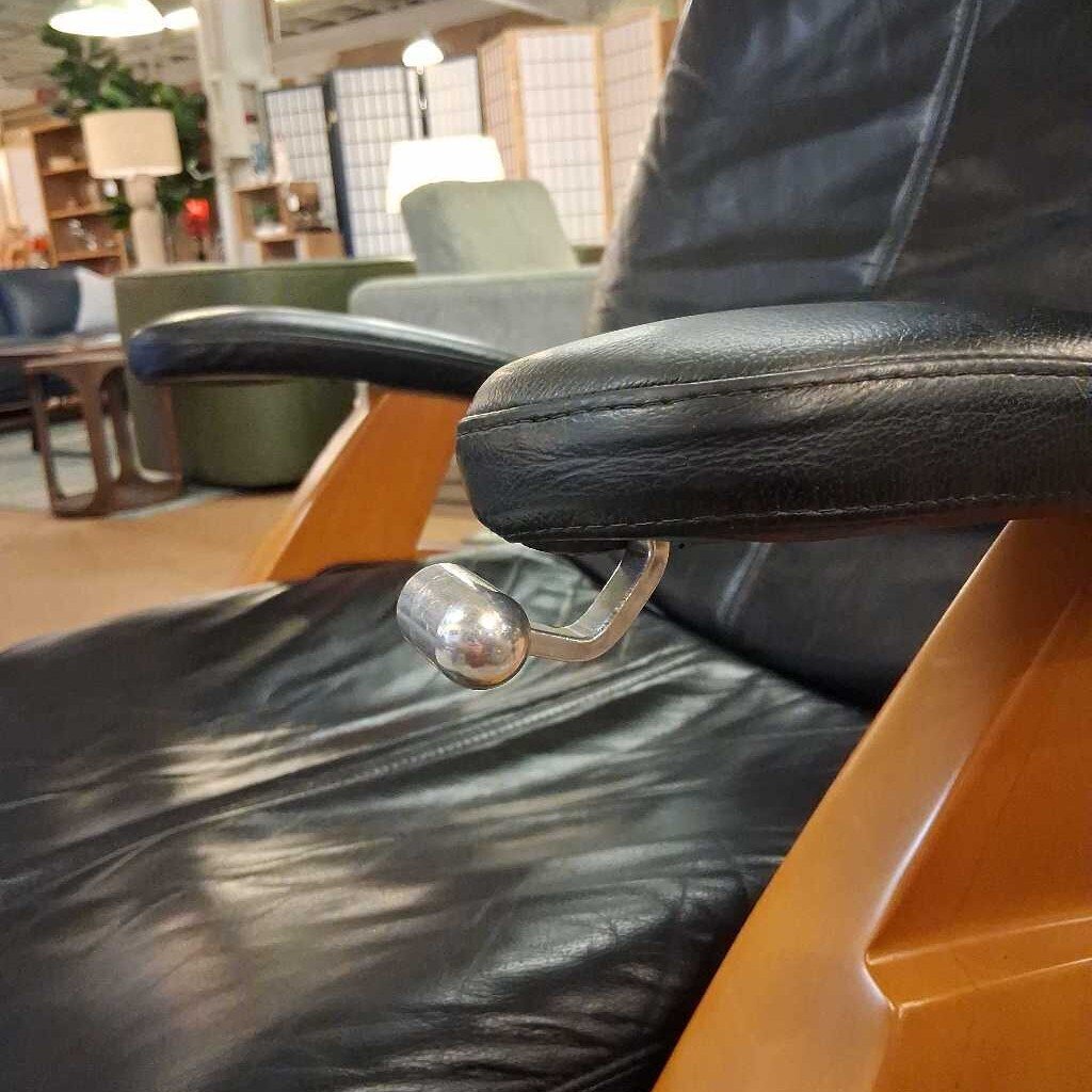Black leather recliner chair in a showroom setting with furniture and decor.