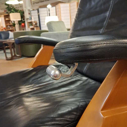 Black leather recliner chair in a showroom setting with furniture and decor.