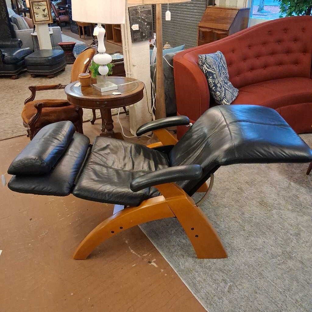 Black leather recliner chair in a showroom setting with furniture and decor.