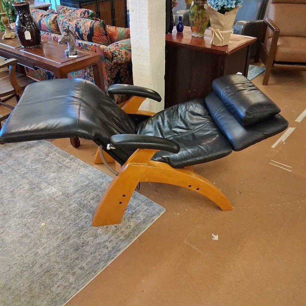 Black leather recliner chair with wooden frame in a room with furniture and decor.