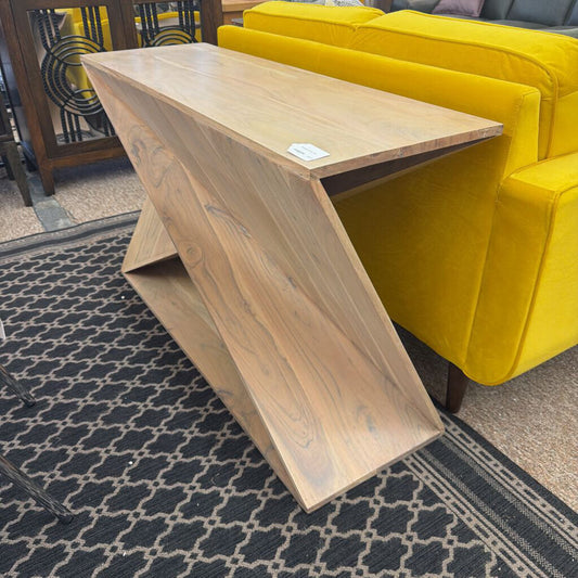 Wooden console table on a patterned rug with a yellow sofa in the background