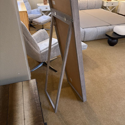 Easel stand with a wooden board in an indoor setting, possibly a furniture store.