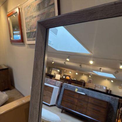 Framed mirror reflecting a room with furniture and decor
