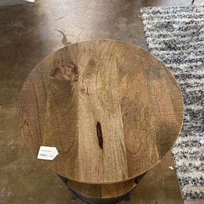 Round wooden table top with a visible label on a concrete floor.