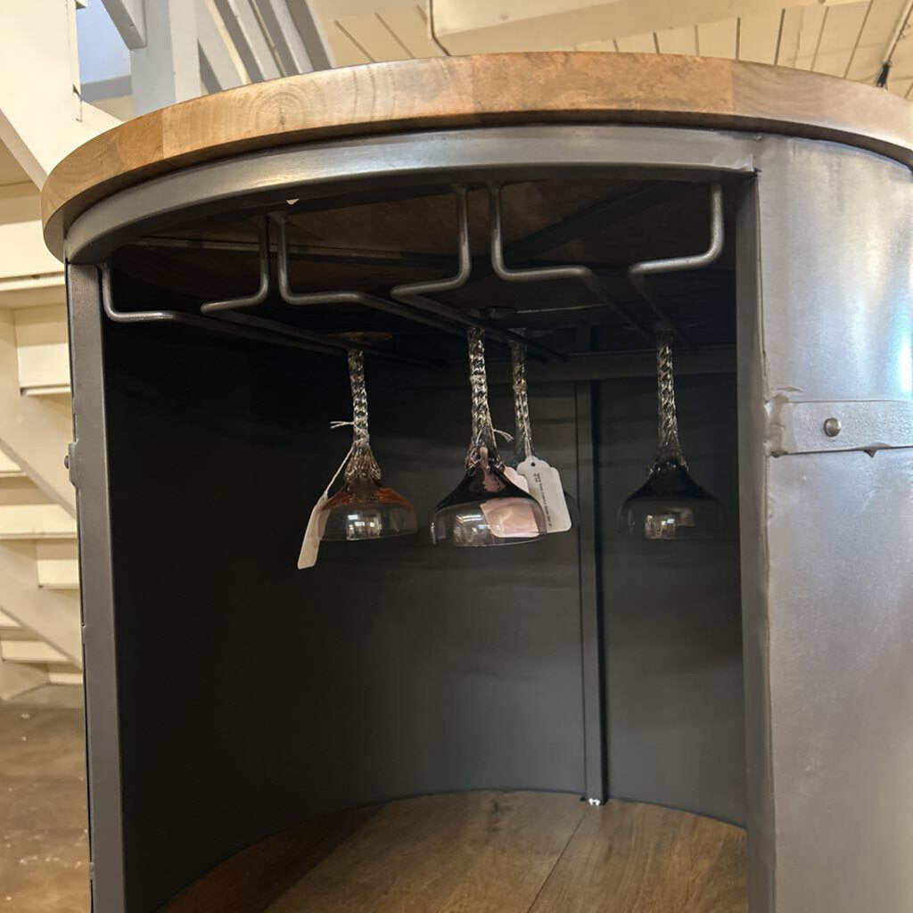 Metallic cabinet with hanging glass objects in a room with wooden floor and white walls.