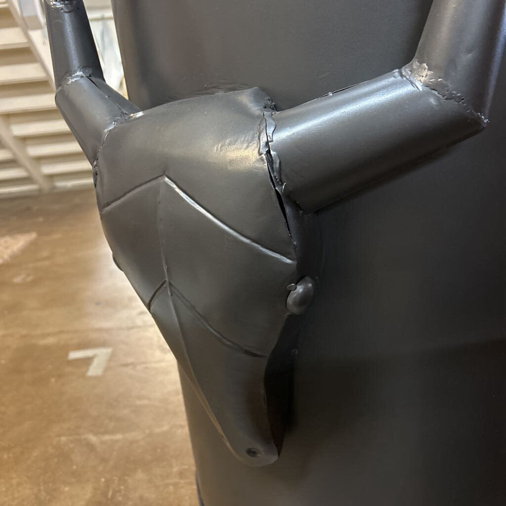 Close-up of a gray metal pipe with a elbow joint on a concrete floor.