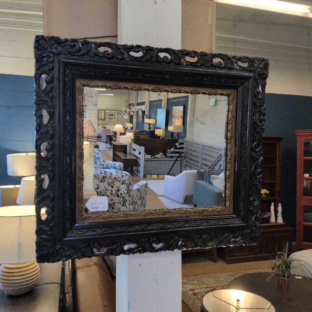 Decorative mirror with ornate black frame in a room setting